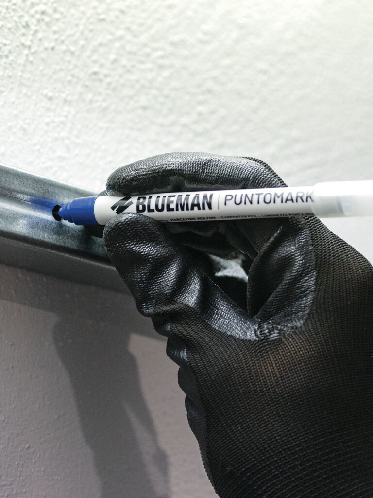 Pennarello Puntomark in uso del brand Blueman, prodotto e distribuito da Ullmann. Marcatore professionale con terminale in metallo lungo 20 mm per segnare attraverso i fori. Utile in fase di montaggio di mobili, infissi, mensole, sistemi di illuminazione, ecc. L’inchiostro permanente a base alcool garantisce una marcatura precisa e duratura su legno, metallo, gomma, plastica e materiali simili. Tappo posizionabile sul retro con clip di aggancio.